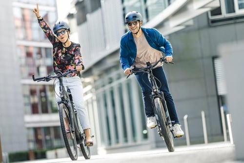 Deux personnes font joyeusement du vélo en ville.
