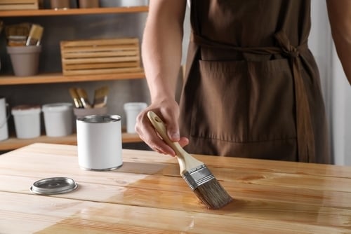 Une femme vernit une table en bois.